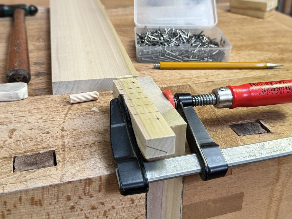 A Bessey F clamp holding a marked part to the edge of the bench