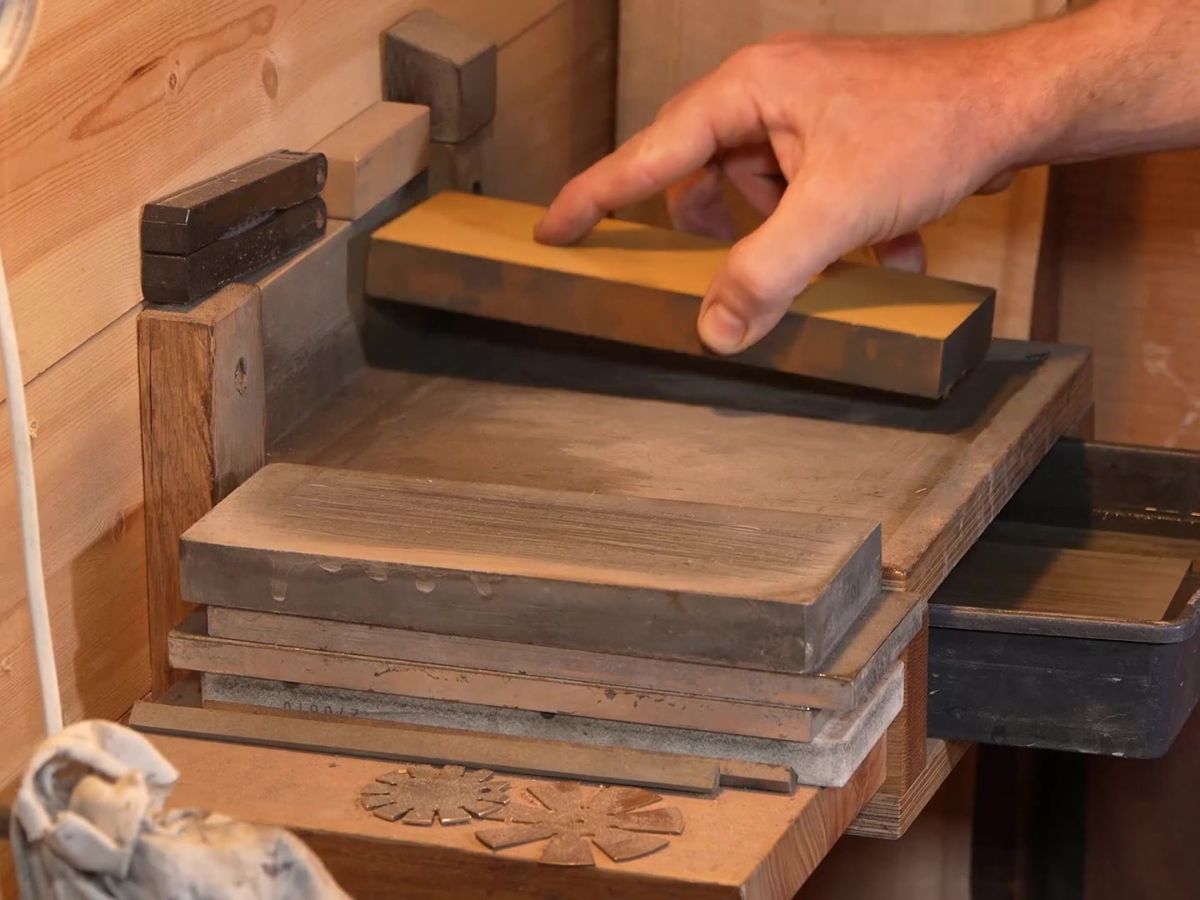 Norton waterstones stacked in Rafael's sharpening station, his hand on the top stone